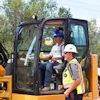 a man in a construction vehicle with a man in a safety vest