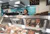 a woman standing behind a display case with food