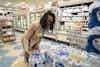 a woman in a store picking up water bottles