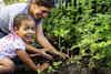 a woman and a girl planting a plant