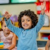 a child raising their hands in a classroom