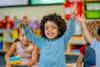 a child raising their hands in a classroom