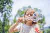 a girl blowing bubbles outside