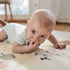 a baby lying on its stomach on a mat