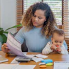 a woman holding a baby and looking at a paper