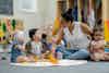 a woman sitting on the floor with babies playing with toys