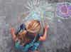a girl drawing with chalk on the ground