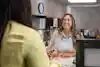 a woman sitting at a desk with another woman in the background