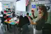 a woman standing in front of a classroom with a screen and a woman raising her hands