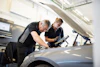 a man and woman working on a car