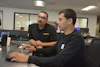 a man looking at a man sitting at a computer