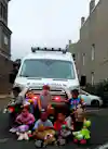 a group of children sitting in front of a ambulance