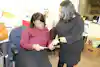 a woman looking at a woman holding a piece of paper